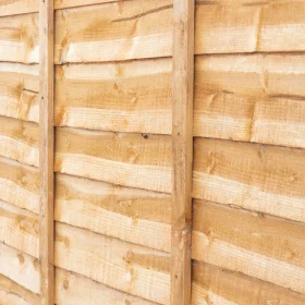 A close up angled view of a gold dip treated timber lap panel.