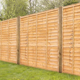 A set of installed gold dipped timber lap fence panels in a garden with posts on grass