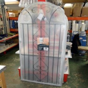 Black metal garden gate with bow top design, shown installed. Features traditional iron-style appearance and adjustable fixings for easy fitting.