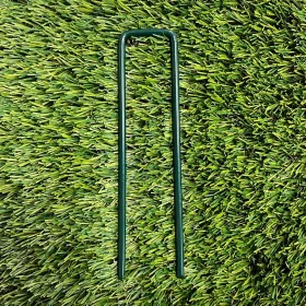 A full view on artificial grass of a green coated u shaped pin.