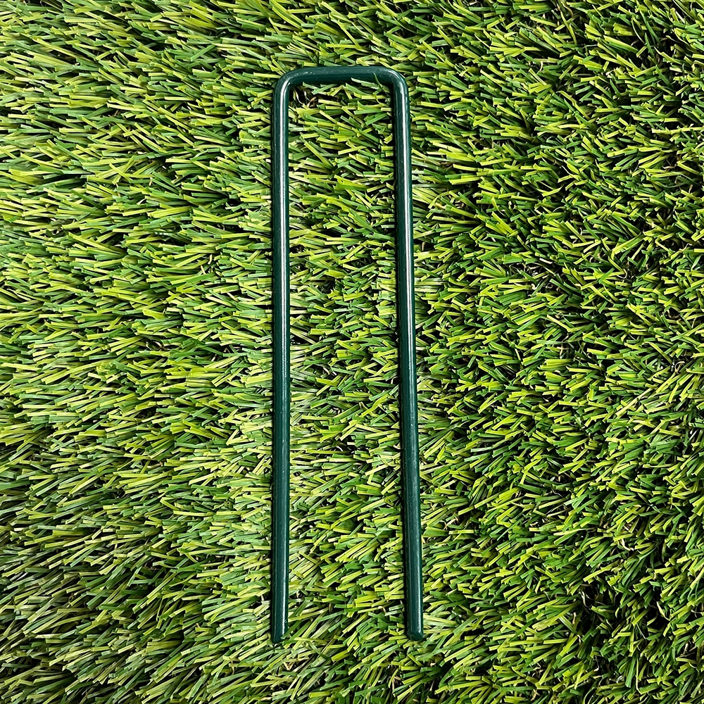 A full view on artificial grass of a green coated u shaped pin.