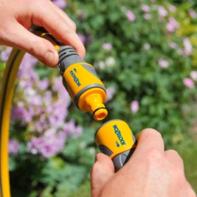 A Hozelock Double Male Adaptor being used to connect two hose ends together in a garden