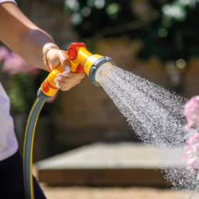 The Hozelock Multi Spray Gun Soft Touch being used to water a plant in a garden