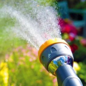 The Hozelock Mutli Spray Pro Gun spraying water using the Rose spray setting over some flowers in a garden