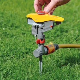 Step 2 for the Hozelock Pulsating Sprinkler controls shown with a hand rotating red dial to control the yellow deflector
