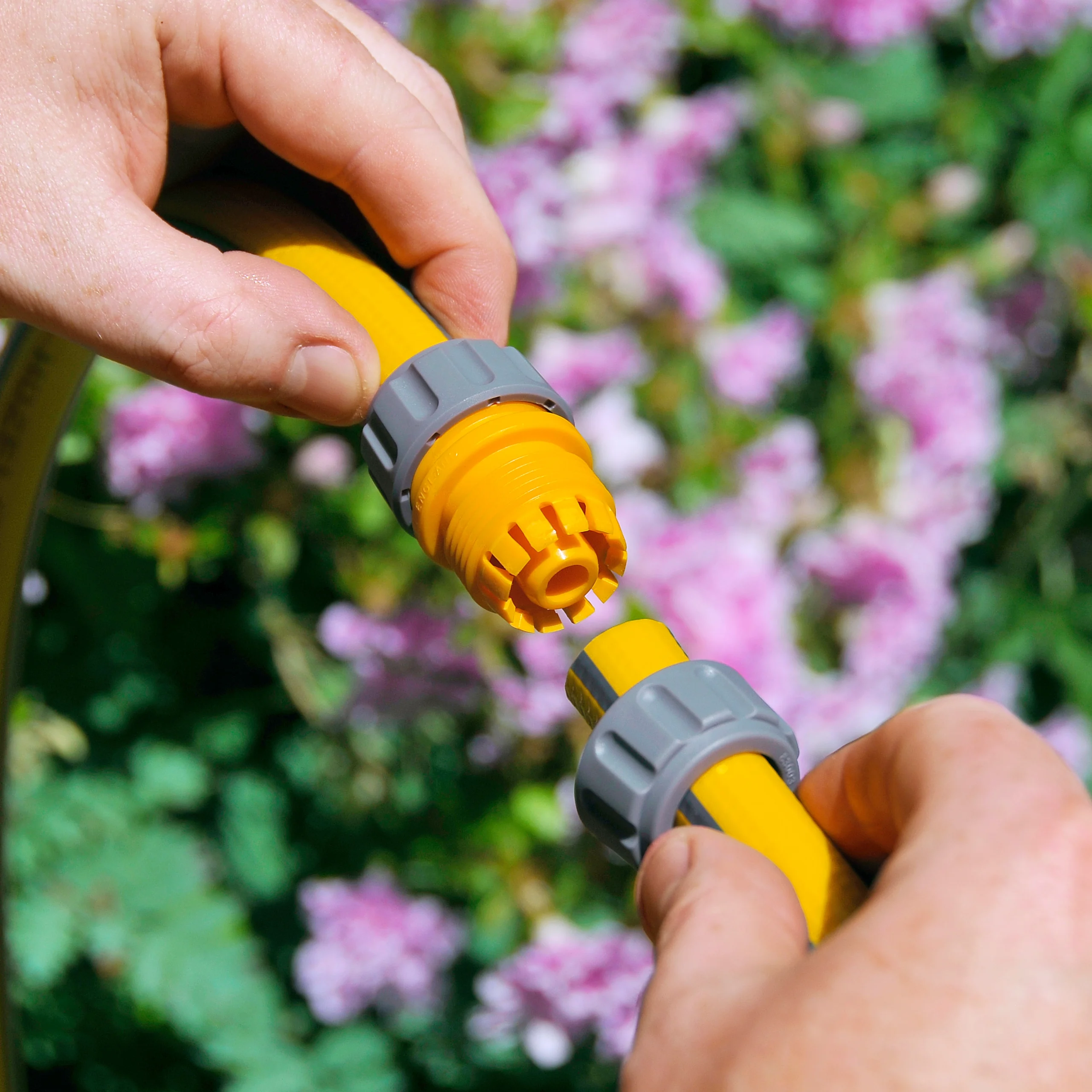 The Hozelock Repair Connector being use to connect two loose hose ends together in a garden
