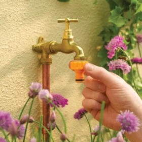 The Hozelock Threaded Tap Connector being connected to an outdoor brass tap against a wall