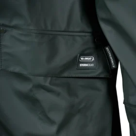 Close-up of pocket detail on green waterproof jacket featuring No-Sweat Stormgear branding and flap closure – durable outerwear for wet and rugged conditions.