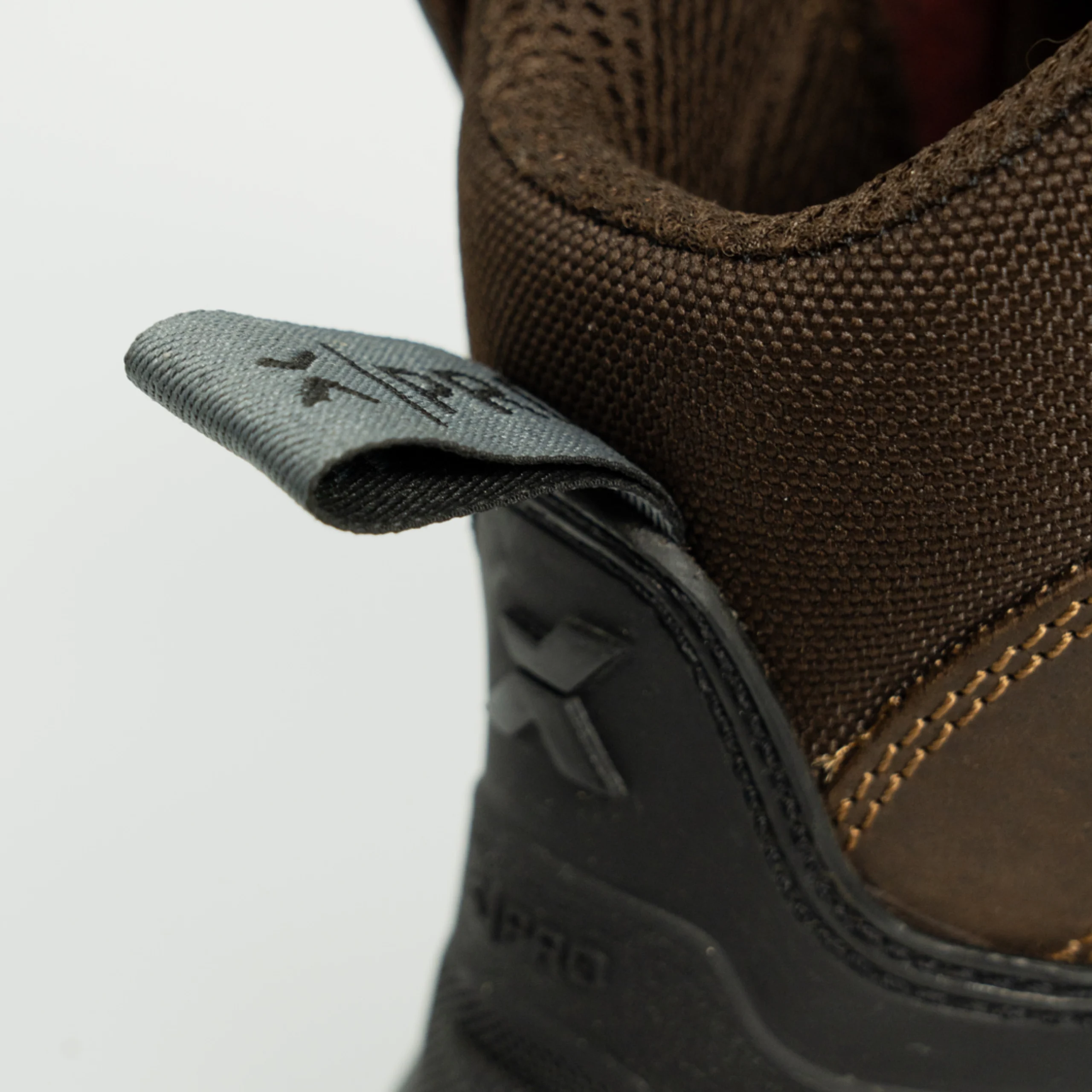 Rear close-up of brown work boots showing reinforced heel support, branded pull loop, and heavy-duty stitching for enhanced durability.