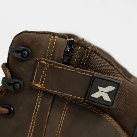 Close-up of brown work boots showing side zip fastening, reinforced stitching, and durable fabric collar for added ankle support.