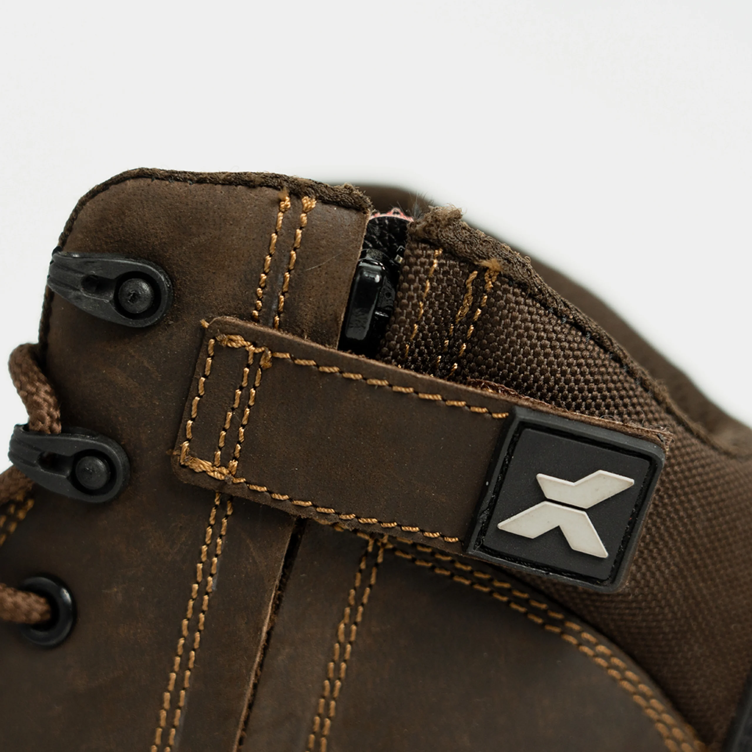 Close-up of brown work boots showing side zip fastening, reinforced stitching, and durable fabric collar for added ankle support.