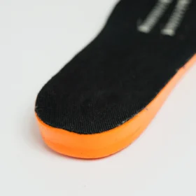 Close-up of cushioned insole from brown work boots, featuring black fabric upper layer and vibrant orange foam for enhanced foot support and shock absorption.