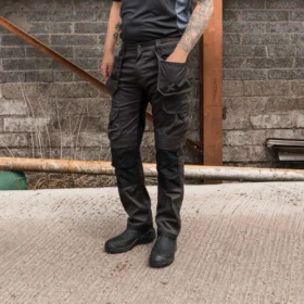 Man wearing Pro Stretch Plus grey and black work trousers with multiple cargo pockets and reinforced knees, ideal for tough worksite conditions.