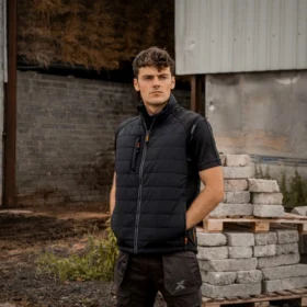 Man wearing a gilet body warmer outdoors on a yard - durable and stylish black body warmer perfect for workwear layering.
