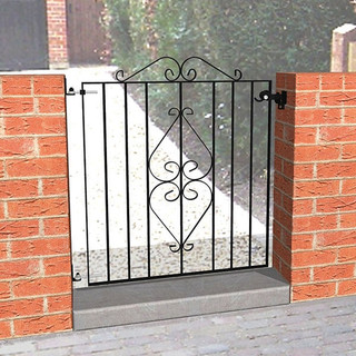 Black decorative metal side gate in between two brick walls.